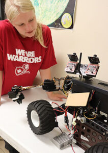 Female student looking at remote controlled robotic car